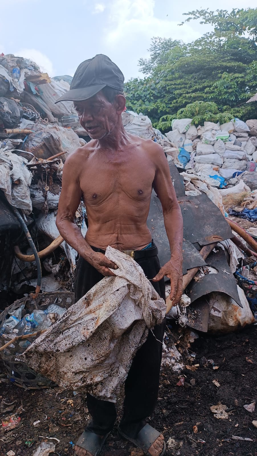 Yanto (72), sedang memilah barang bernilai ekonomis dari tumpukan sampah. (Gede Sweta Getas)