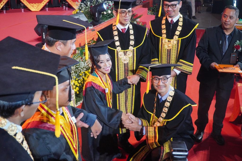 Rektor UNHI Dr. Cokorda Gde Bayu Putra, (depan tengah) menyalami salah satu Wisudawati.